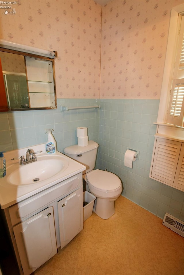 bathroom with vanity, toilet, and tile walls