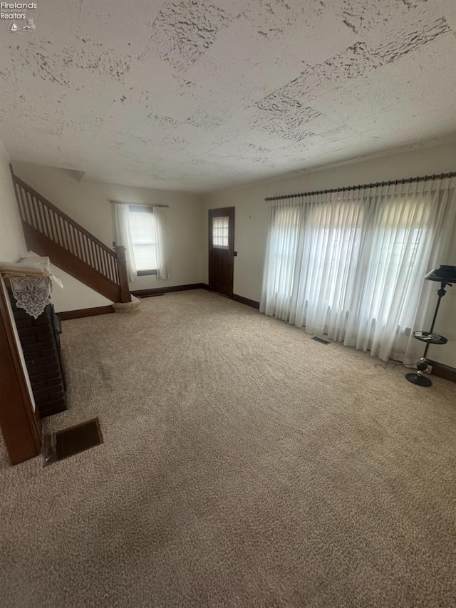 unfurnished living room featuring a textured ceiling and carpet