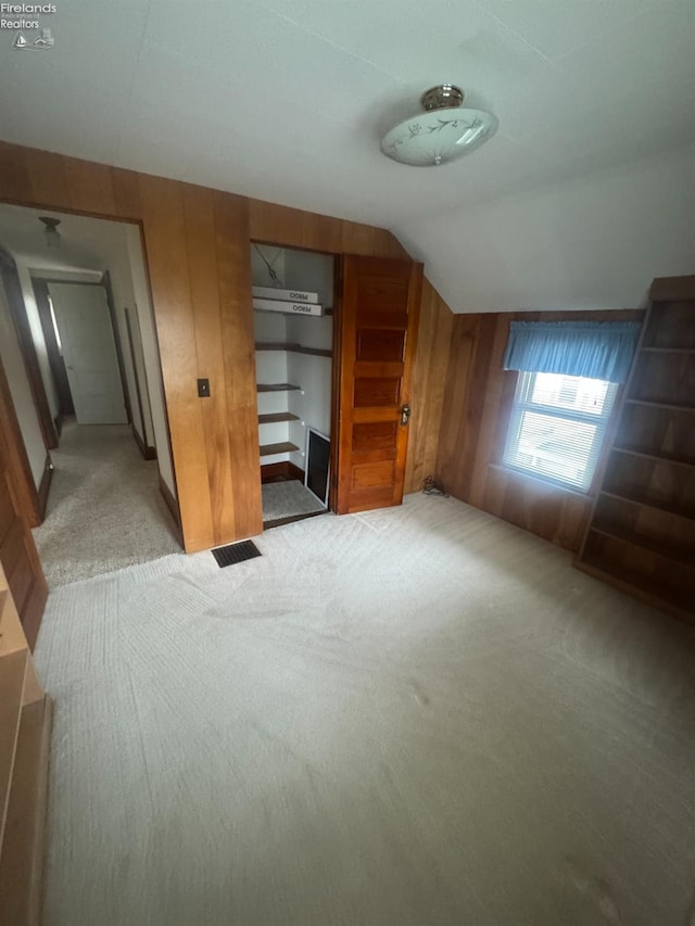 bonus room with light colored carpet, lofted ceiling, and wooden walls