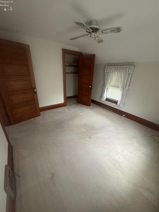 unfurnished bedroom featuring ceiling fan, light colored carpet, lofted ceiling, and a closet