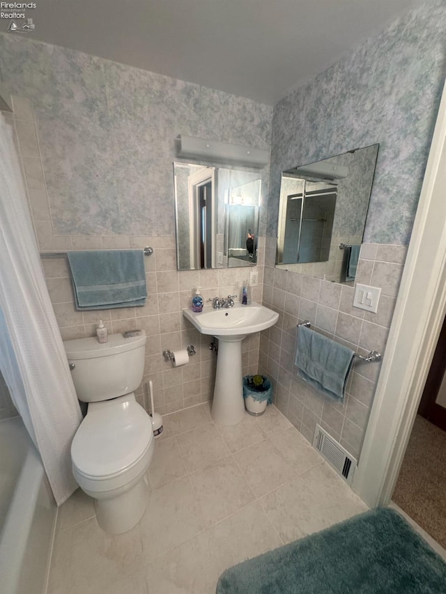 bathroom featuring sink, toilet, tile patterned flooring, and tile walls