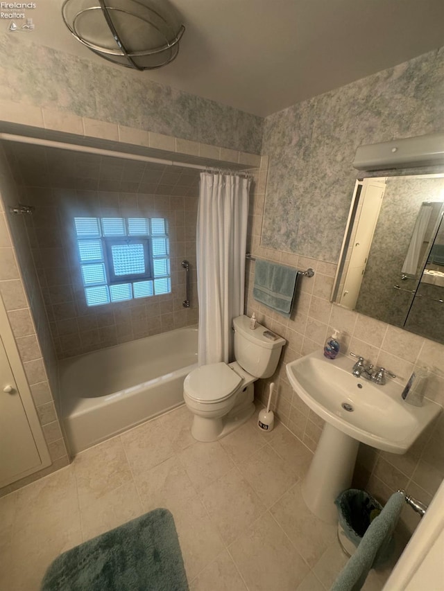 full bathroom with sink, tile walls, tile patterned flooring, toilet, and shower / bath combo with shower curtain