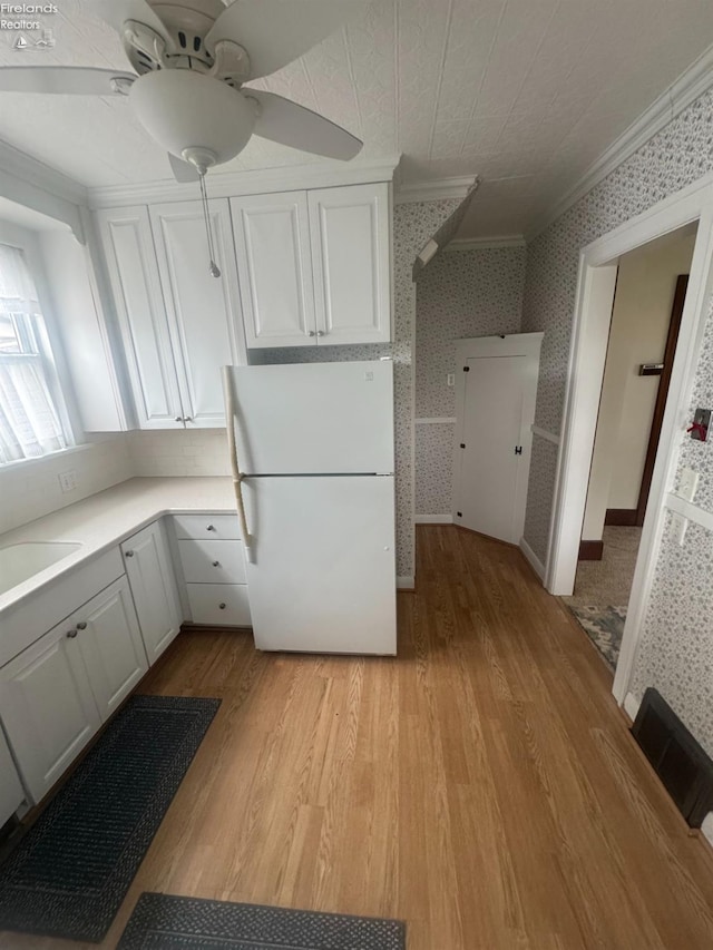 kitchen featuring white cabinetry, white refrigerator, ornamental molding, ceiling fan, and light hardwood / wood-style floors