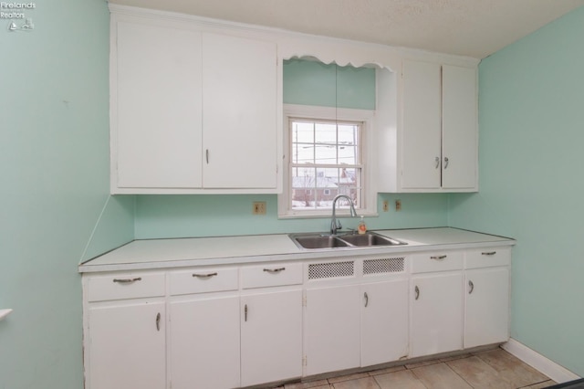 kitchen featuring light tile patterned flooring, white cabinetry, and sink