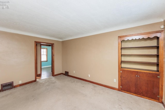 unfurnished room with a textured ceiling and light colored carpet