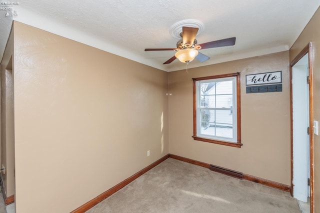 carpeted spare room featuring ceiling fan and a textured ceiling