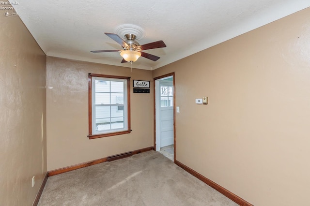 unfurnished room featuring a textured ceiling, ceiling fan, and light colored carpet