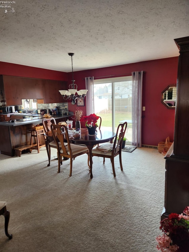 carpeted dining room with an inviting chandelier and a textured ceiling