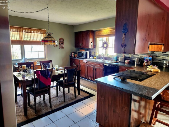 kitchen featuring decorative light fixtures, a breakfast bar, decorative backsplash, and black appliances