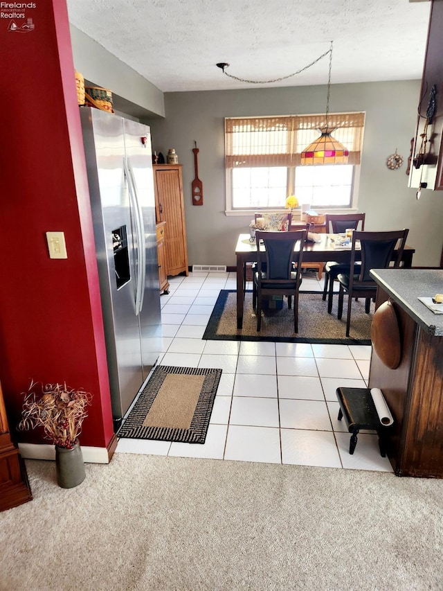 tiled dining space with a textured ceiling