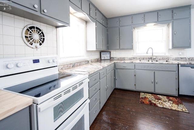 kitchen with range with two ovens, backsplash, a sink, and stainless steel dishwasher