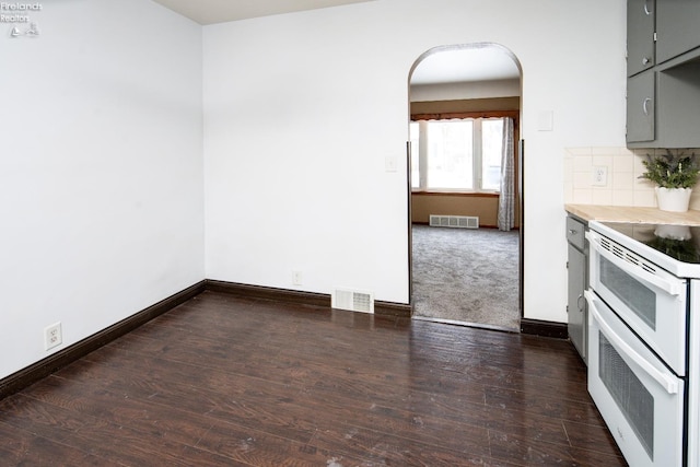 kitchen with range with two ovens, gray cabinets, visible vents, decorative backsplash, and dark wood-type flooring