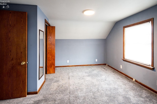 additional living space with lofted ceiling, baseboards, and light colored carpet