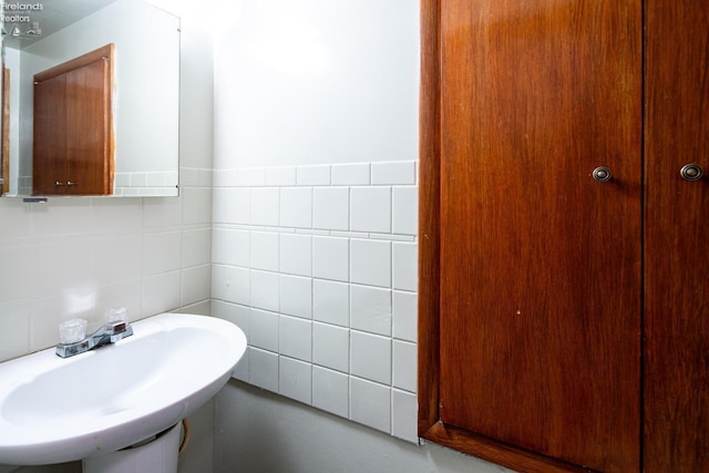 bathroom featuring tile walls and a sink