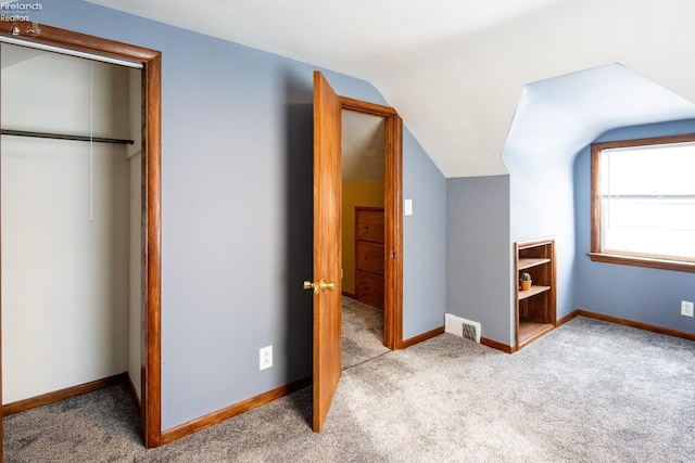 unfurnished bedroom with lofted ceiling, light carpet, visible vents, and a closet