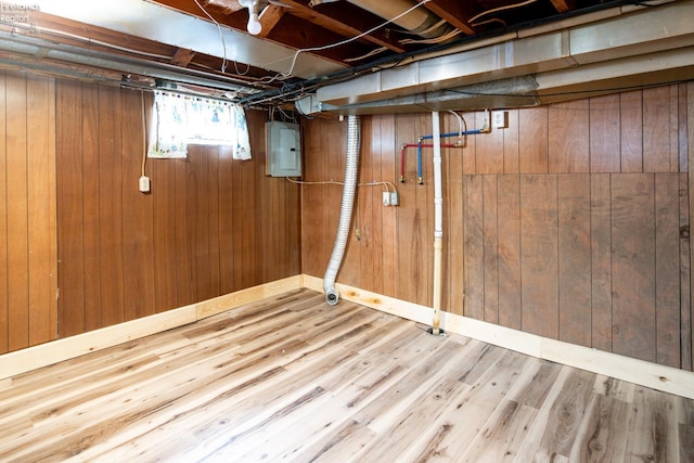 basement featuring electric panel, wood walls, and wood finished floors