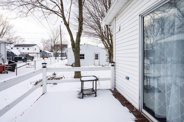 snow covered patio with a residential view and fence