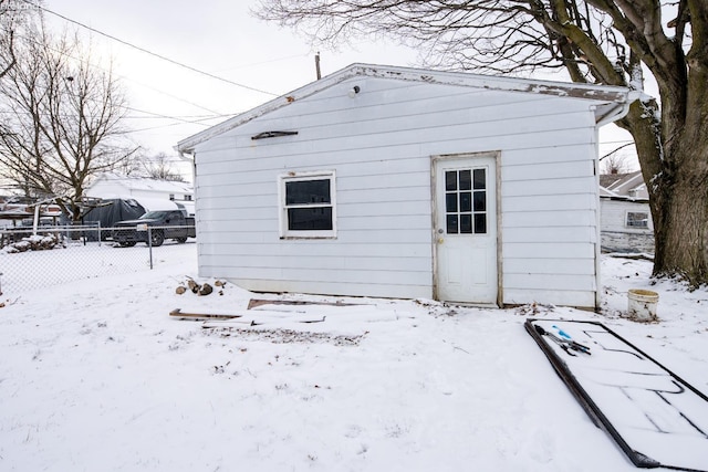 snow covered structure featuring a garage and fence