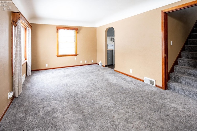 carpeted spare room featuring arched walkways, visible vents, stairway, and baseboards