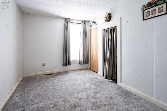 carpeted spare room with a drop ceiling