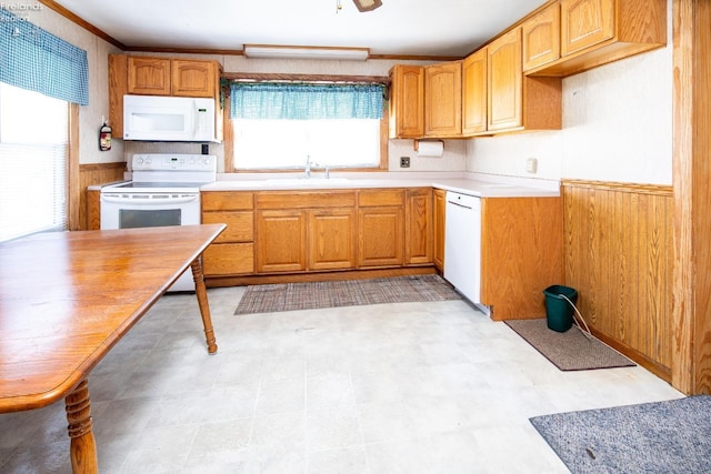 kitchen with white appliances, sink, and wood walls