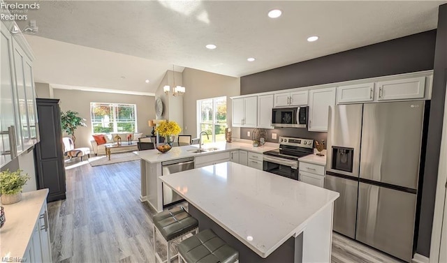 kitchen with sink, appliances with stainless steel finishes, hanging light fixtures, a kitchen breakfast bar, and kitchen peninsula