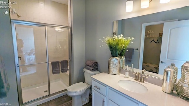 bathroom with vanity, wood-type flooring, a shower with door, and toilet