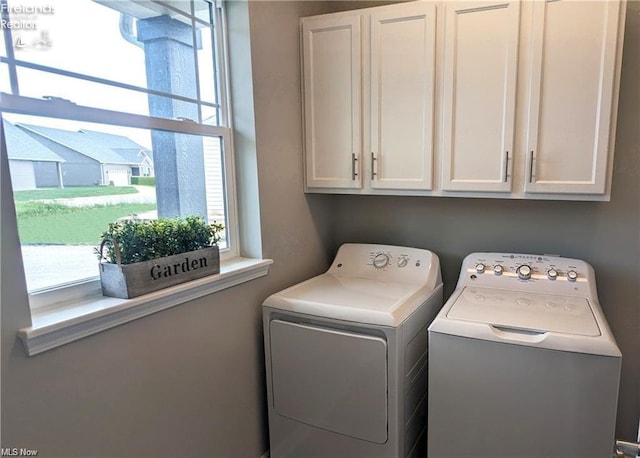 laundry room featuring washer and clothes dryer and cabinets