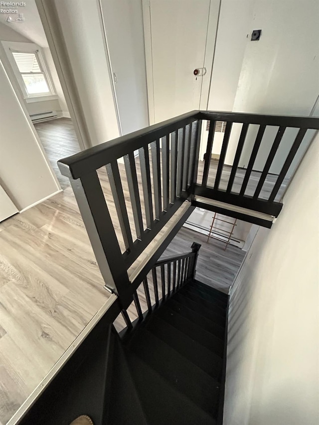 staircase featuring wood-type flooring and baseboard heating