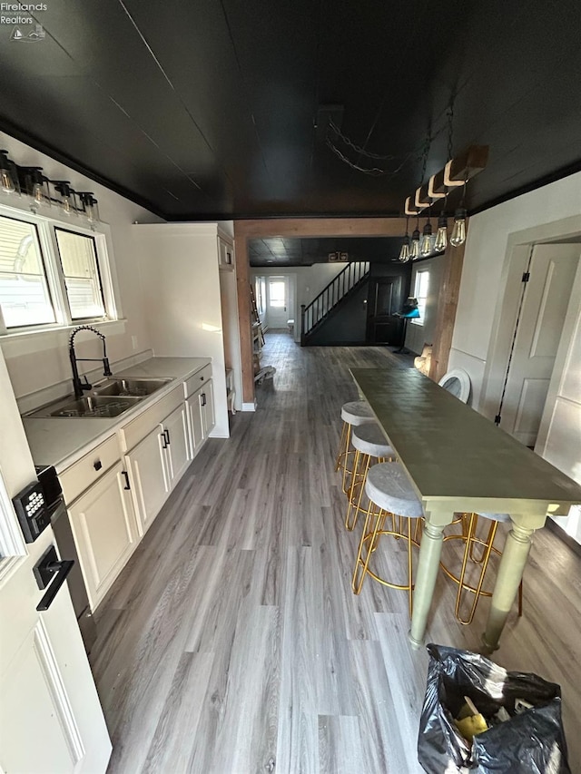 kitchen with sink, light hardwood / wood-style flooring, and white cabinets