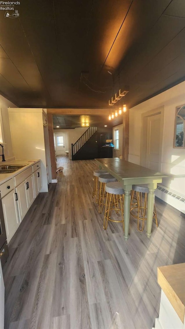 unfurnished dining area featuring a baseboard heating unit, sink, and light hardwood / wood-style flooring