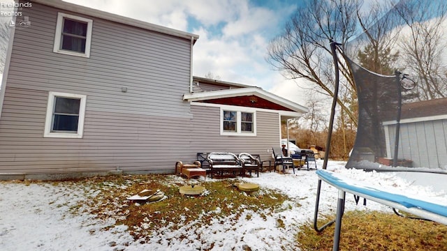 snow covered back of property featuring a trampoline