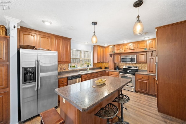 kitchen featuring sink, hanging light fixtures, a kitchen breakfast bar, stainless steel appliances, and a center island