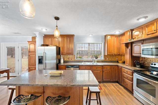 kitchen featuring stainless steel appliances, sink, a center island, and a breakfast bar area