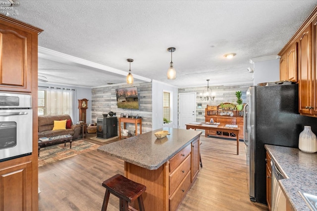 kitchen with ornamental molding, appliances with stainless steel finishes, a kitchen bar, and light hardwood / wood-style floors