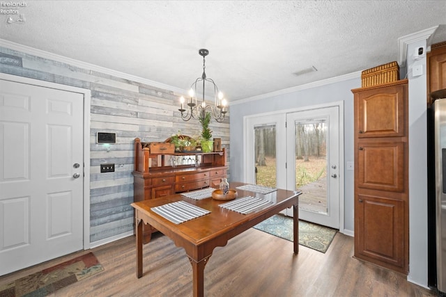 dining area featuring ornamental molding, dark wood-type flooring, a textured ceiling, and an inviting chandelier