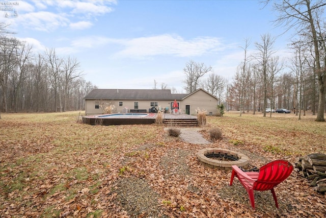 back of house featuring a pool side deck and a fire pit