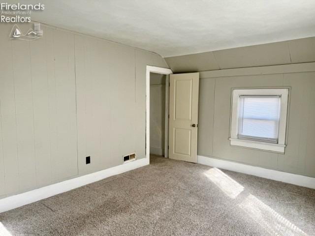 unfurnished bedroom with lofted ceiling, carpet, visible vents, and baseboards