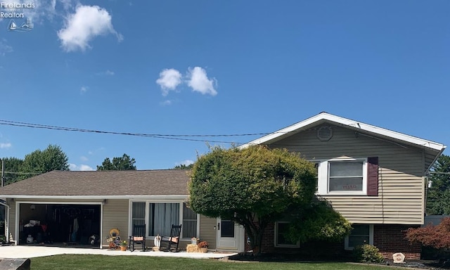 view of front facade with brick siding, roof with shingles, concrete driveway, a garage, and a front lawn