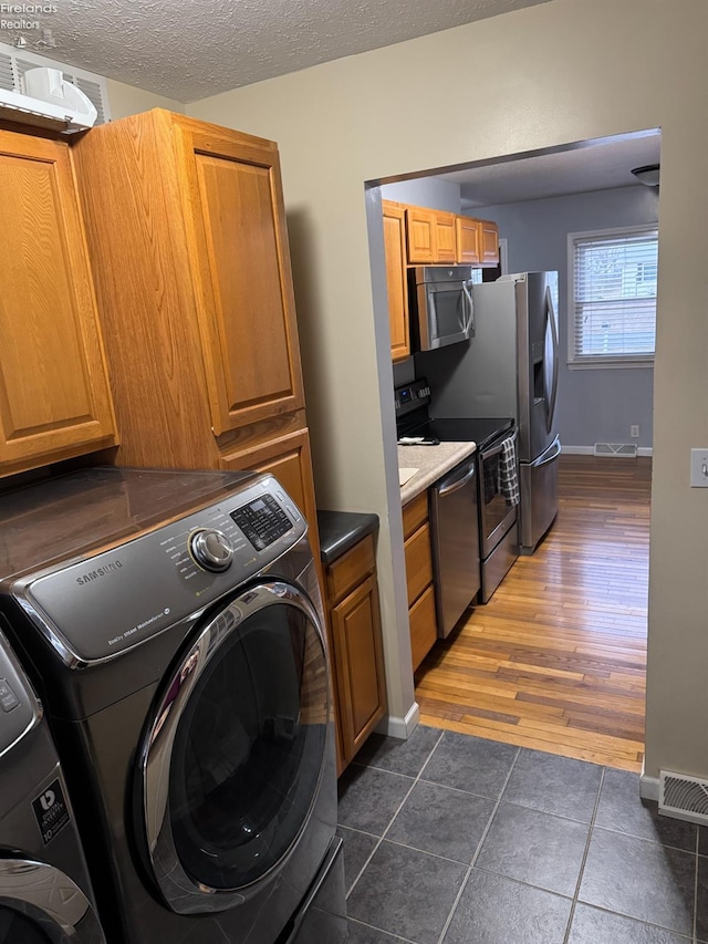 laundry room featuring dark tile patterned floors, a textured ceiling, and independent washer and dryer