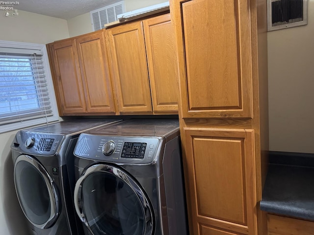 washroom with cabinets, washing machine and clothes dryer, and a textured ceiling