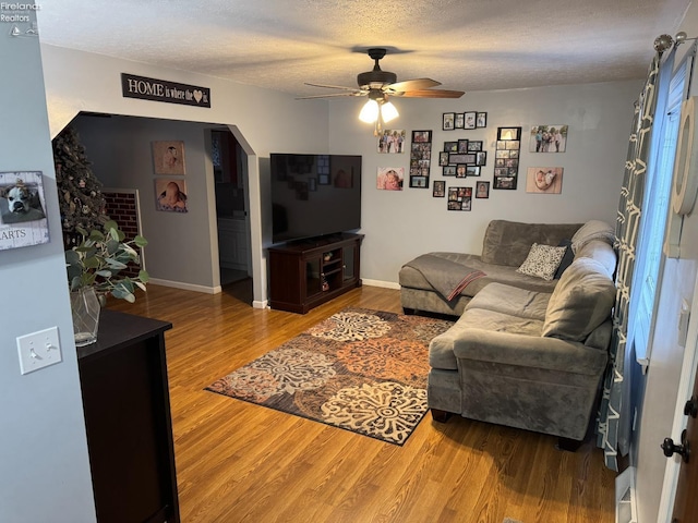 living room with ceiling fan, wood-type flooring, and a textured ceiling