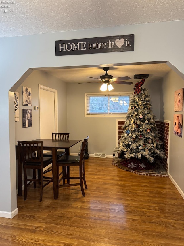 dining room featuring ceiling fan, hardwood / wood-style floors, and a textured ceiling