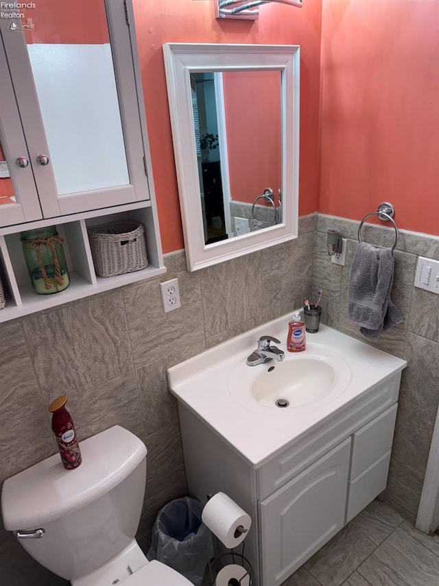 bathroom featuring vanity, toilet, and tile walls