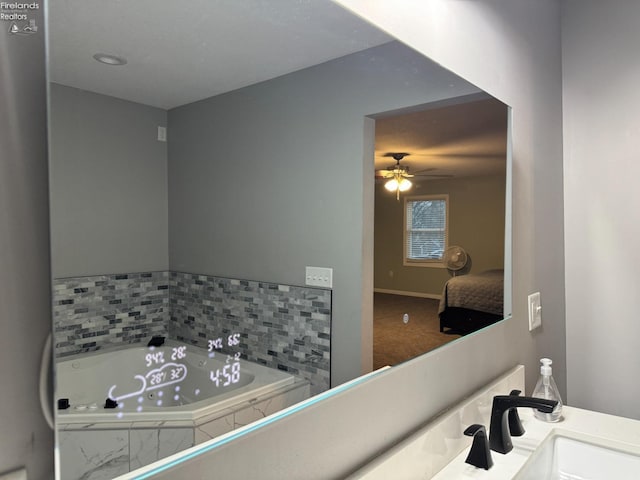 bathroom with sink, tiled bath, and ceiling fan