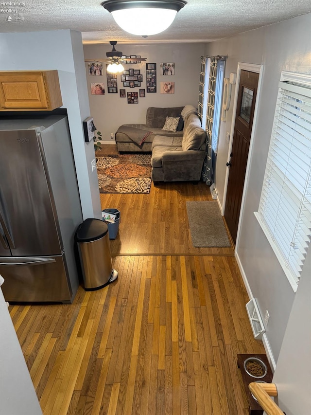 living room featuring hardwood / wood-style floors, a textured ceiling, and ceiling fan