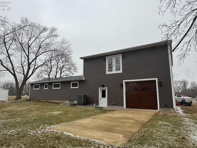 rear view of house featuring a garage, a lawn, and central air condition unit