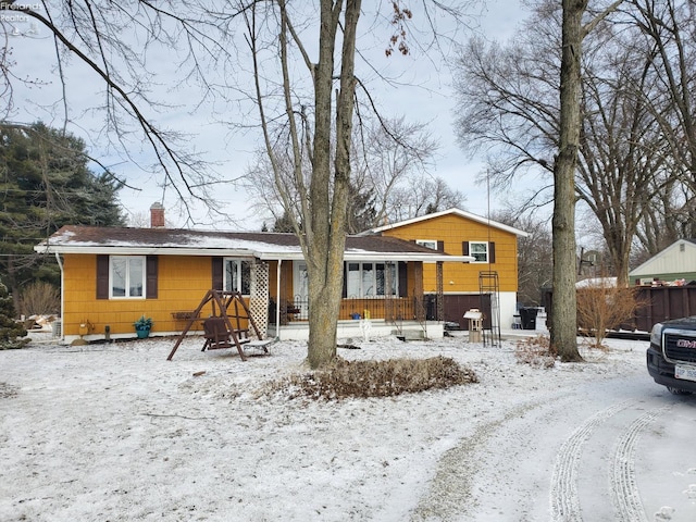 view of front of house featuring a chimney, fence, and covered porch
