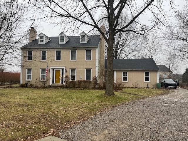 colonial inspired home featuring a chimney and a front yard