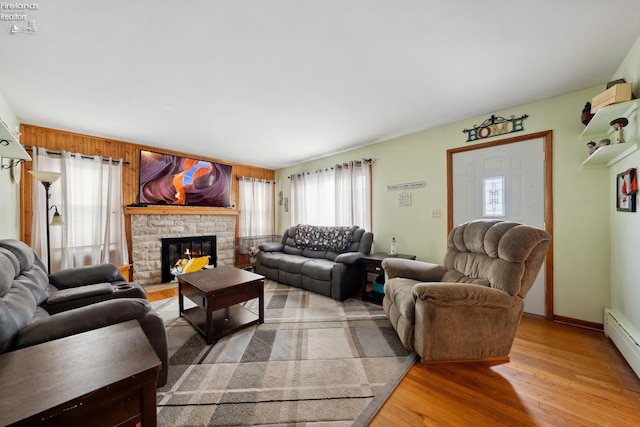 living room with hardwood / wood-style flooring, a baseboard radiator, plenty of natural light, and a fireplace